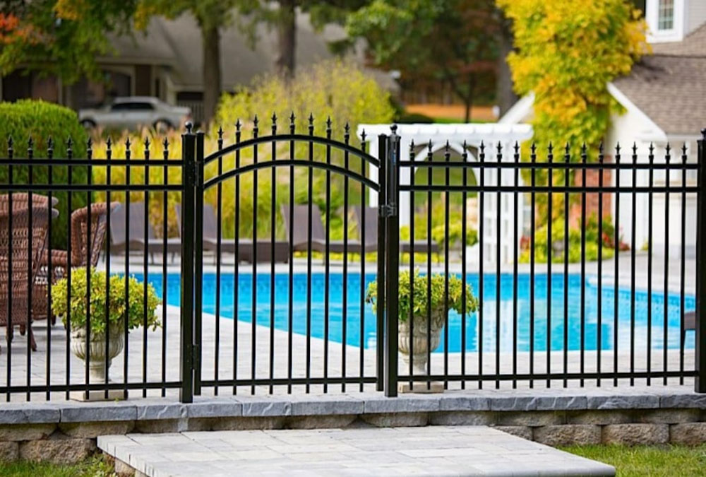 Black ornamental metal fence enclosing a backyard pool area for safety and style